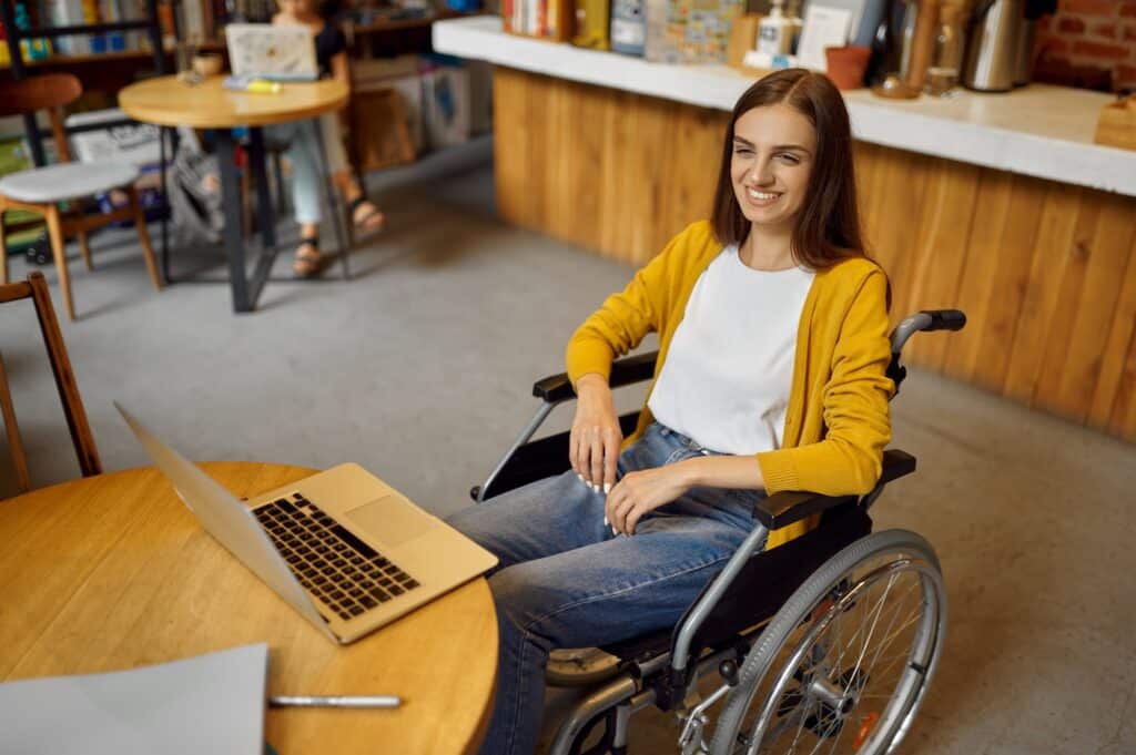 Disabled female student in wheelchair using laptop